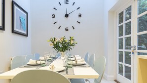 A dining area with a clock, a vase of flowers, and a window with a view. - JOIVY Stunning 3BR house near Regents Park& Baker Street (London)