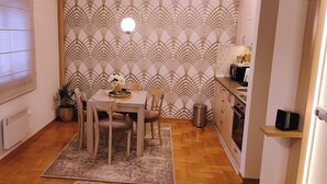A compact kitchen with a dining area, a radiator, a potted plant, and a small shelf with a microwave. - Apartment Bubica Zlatibor Best for Family Holidays and Couples in Love (Zlatibor)