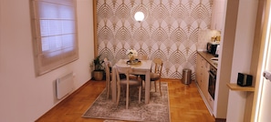 A compact kitchen with a dining area, a radiator, a potted plant, and a small shelf with a microwave. - Apartment Bubica Zlatibor Best for Family Holidays and Couples in Love (Zlatibor)