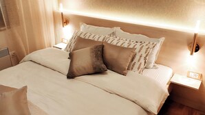 A neatly made bed with patterned pillows, a bedside table with a lamp, and a wall-mounted light fixture. - Apartment Bubica Zlatibor Best for Family Holidays and Couples in Love (Zlatibor)