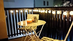 A small round table with a candle and a glass jar, set against a dark wooden backdrop with vertical slats and string lights. - Apartment Bubica Zlatibor Best for Family Holidays and Couples in Love (Zlatibor)