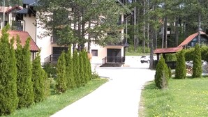 A residential area with a pathway leading to a building with a balcony and a car parked in front. - Apartment Bubica Zlatibor Best for Family Holidays and Couples in Love (Zlatibor)