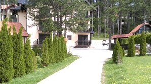 A residential area with a pathway leading to a building with a balcony and a car parked in front. - Apartment Bubica Zlatibor Best for Family Holidays and Couples in Love (Zlatibor)