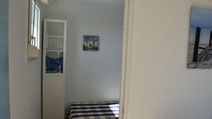 A small room with a checkered bed, a window, and a painting on the wall. - Waterfront apartment (Lacanau Océan)
