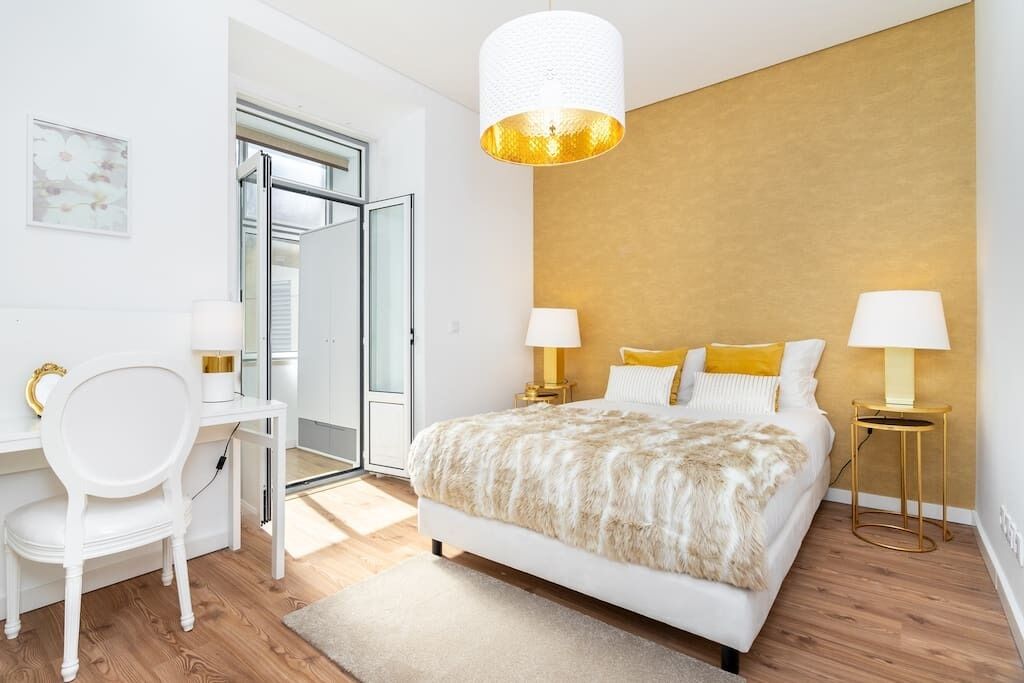 Une chambre à coucher moderne avec un grand lit, deux tables de chevet avec des lampes, un bureau avec une chaise et une grande fenêtre.