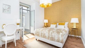 Un dormitorio moderno con una cama grande, dos mesitas de noche con lámparas, un escritorio con una silla y un ventanal amplio.