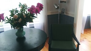 Um quarto com uma mesa redonda, uma cadeira verde e um vaso de flores.