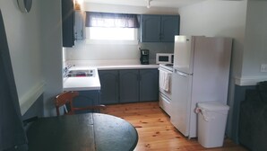 Uma cozinha compacta com uma mesa de jantar, micro-ondas, frigorífico e chão de madeira.