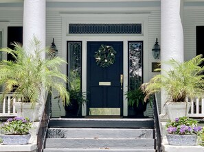 Stunning entrance with a dark blue door, flanked by two columns and potted plants.