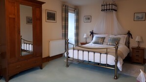 A bedroom with a four-poster bed, a large mirror, a radiator, and a nightstand with a lamp. - No.3 The Old Convent. (Fort Augustus)