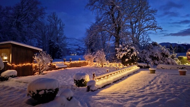 A snow-covered garden with a wooden cabin and string lights. - No.3 The Old Convent. (Fort Augustus)