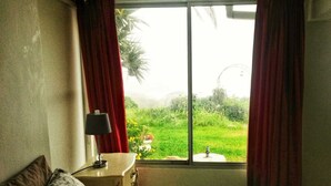 Un dormitorio con cama, mesita de noche, lámpara y ventana con cortinas.