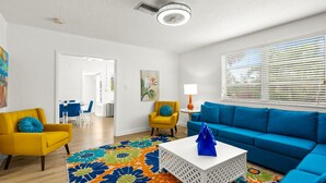 Een moderne woonkamer met een blauwe bank, een gele fauteuil en een witte salontafel.