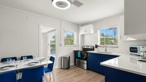 Een moderne keuken met witte kasten, een blauw aanrecht en een roestvrijstalen fornuis.