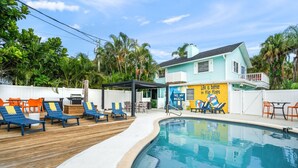 A pool area with lounge chairs and a sign that reads "Life is better in flip flops." - Walk to the Beach | Osprey Villa | Siesta Key (Sarasota)