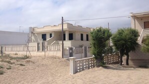 A modern two-story house with a flat roof, a staircase leading to the upper floor, and a gated entrance.
