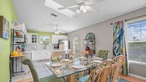 A dining area with a glass table set for six, surrounded by wicker chairs. - Key West Villa 3 min to #1 Beach • Pool • BBQ (Sarasota)