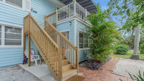 A two-story house with a wooden staircase leading to a balcony. - Key West Villa 3 min to #1 Beach • Pool • BBQ (Sarasota)