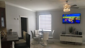 Ein modernes Wohnzimmer mit Essbereich, einem an der Wand montierten Fernseher und einem Deckenventilator.