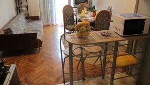A dining area with a table, chairs, a microwave, and a sofa. - Lovely Apartment With a Sea View Apartment (Supetar)
