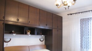 A bedroom with a large bed, wooden headboard, and built-in shelves. - Lovely Apartment With a Sea View Apartment (Supetar)