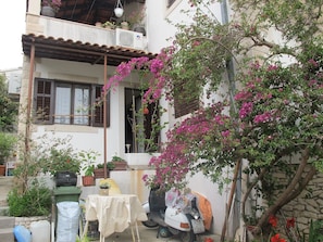 A residential building with a balcony, potted plants, a scooter, and a table with a tablecloth. - Lovely Apartment With a Sea View Apartment (Supetar)