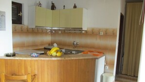 A small kitchen with wooden cabinets, a sink, and a fruit bowl containing bananas and apples. - Lovely Apartment With a Sea View Apartment (Supetar)