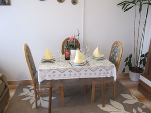 A dining table set with plates, a wine bottle, and a vase with flowers. - Lovely Apartment With a Sea View Apartment (Supetar)