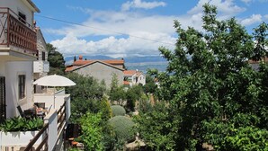 A residential area with a balcony, a white umbrella, and a view of mountains. - Lovely Apartment With a Sea View Apartment (Supetar)