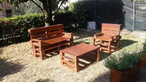 Un espace extérieur aménagé avec des meubles en bois, comprenant un banc et deux chaises.