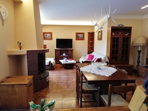 A living room with a fireplace, a television, a dining table with chairs, and a sofa.