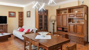 Un salon comprenant un canapé, une table à manger avec des chaises, des meubles en bois et un téléviseur.