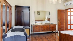 Une chambre à coucher comprenant un lit, une commode, une armoire, un miroir et un lustre.