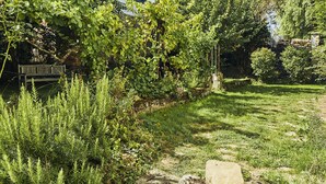 A garden with a stone pathway, lush greenery, and a wooden bench.