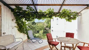 A covered patio with a table and chairs, a wicker sofa, and a red chair.