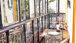 Un balcón con una mesa preparada para dos, una silla y una botella de vino.