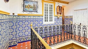 Una escalera con barandillas negras ornamentadas y una pared con diseño azul y blanco.