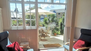 Ein sonnendurchflutetes Zimmer mit zwei Stühlen, einem Tisch und Blick auf einen Garten durch ein Fenster.