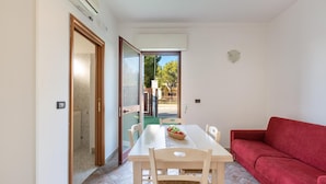 Un coin repas avec une table, des chaises et un canapé rouge.