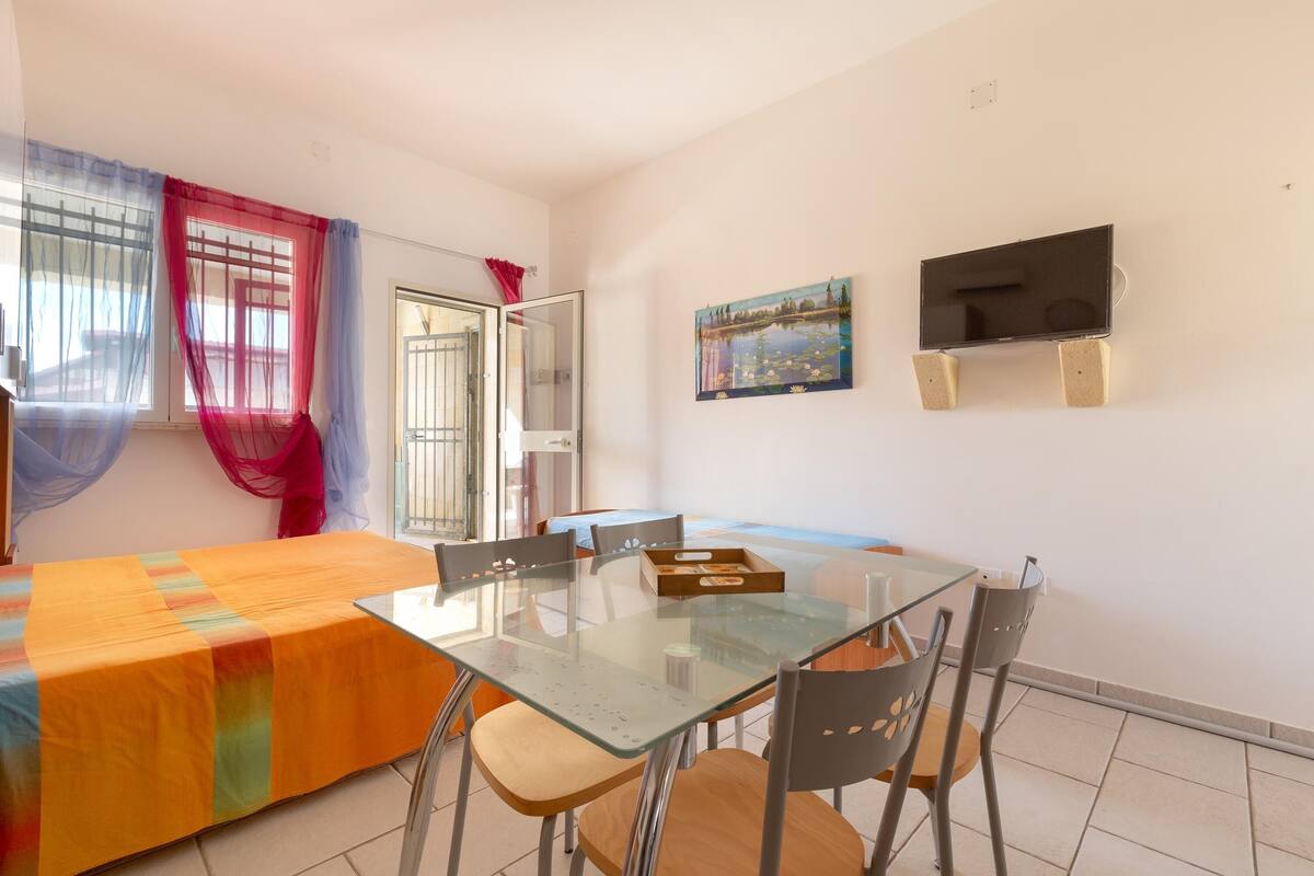 A dining area with a glass table, chairs, and a colorful tablecloth.