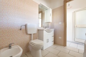 A bathroom with a toilet, bidet, sink, and mirror. - Residence Aquarium (Torricella)