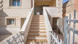 A staircase leading to a building entrance with a metal railing and a view of the sky. - Residence Aquarium (Torricella)