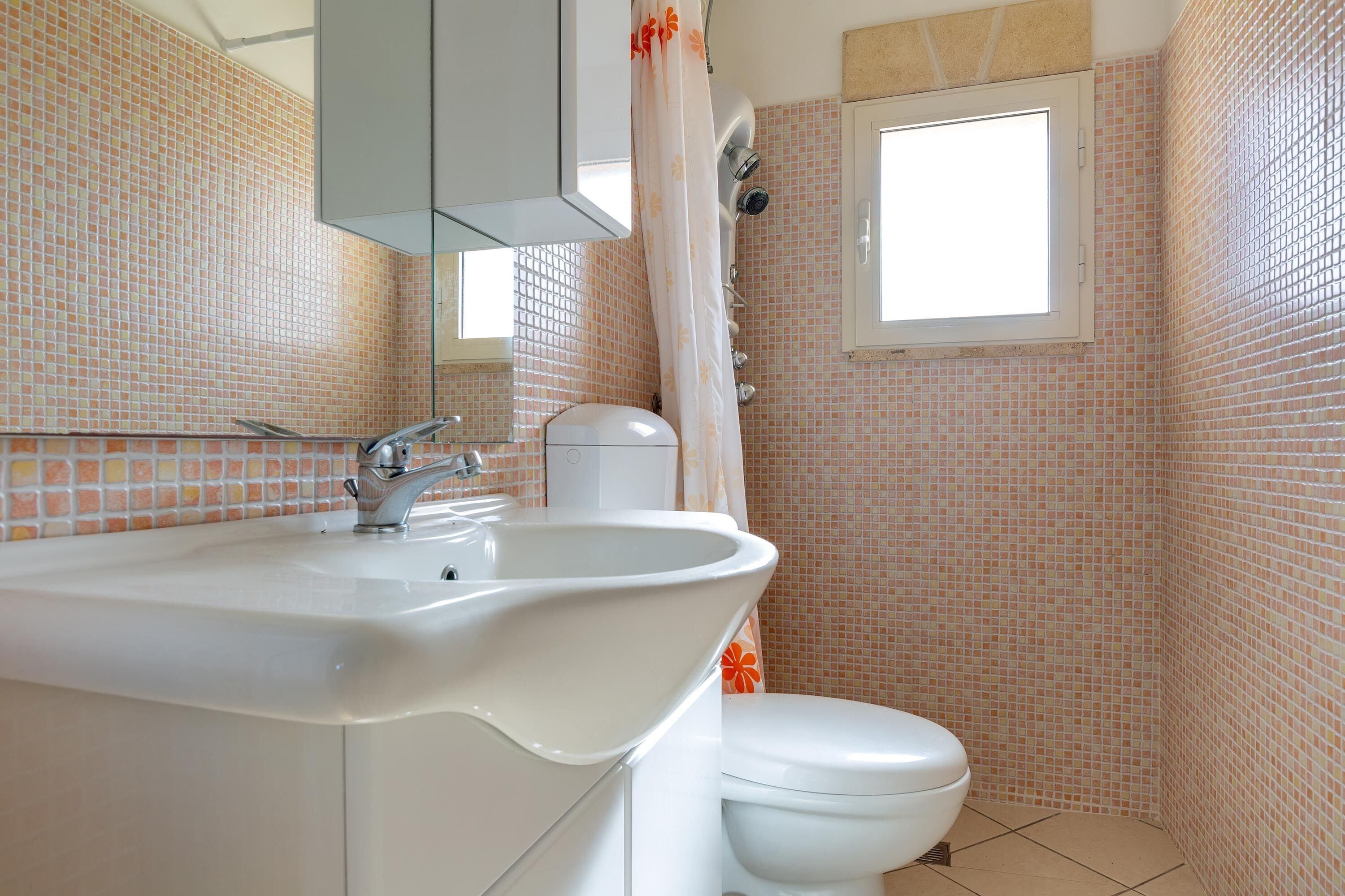 Un baño con lavamanos, inodoro y cortina de ducha blancos.
