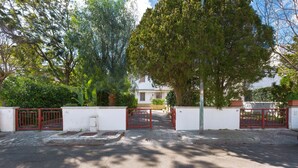 A gated entrance with a white building in the background, surrounded by trees and greenery. - Villetta Amilcare (Lecce)