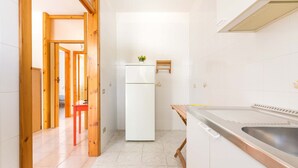 A compact kitchen with a white refrigerator, a wooden table, and a stainless steel sink. - Villetta Amilcare (Lecce)