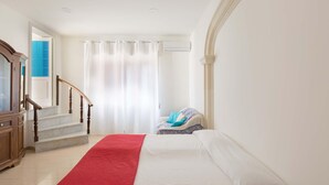 Une chambre d’hôtel avec un lit, un tapis rouge, un escalier et une vue sur une pièce bleue.