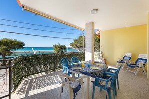 Een balkon met een tafel gedekt voor twee personen, stoelen en uitzicht op zee.