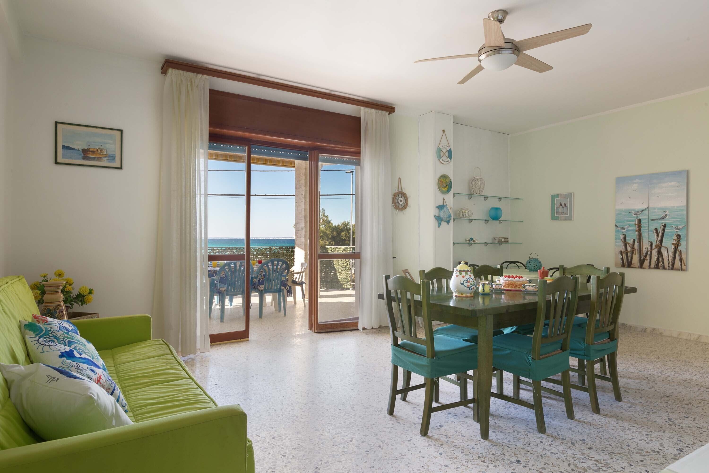 A dining area with a table and chairs, a ceiling fan, and a view through a glass door to the outside.