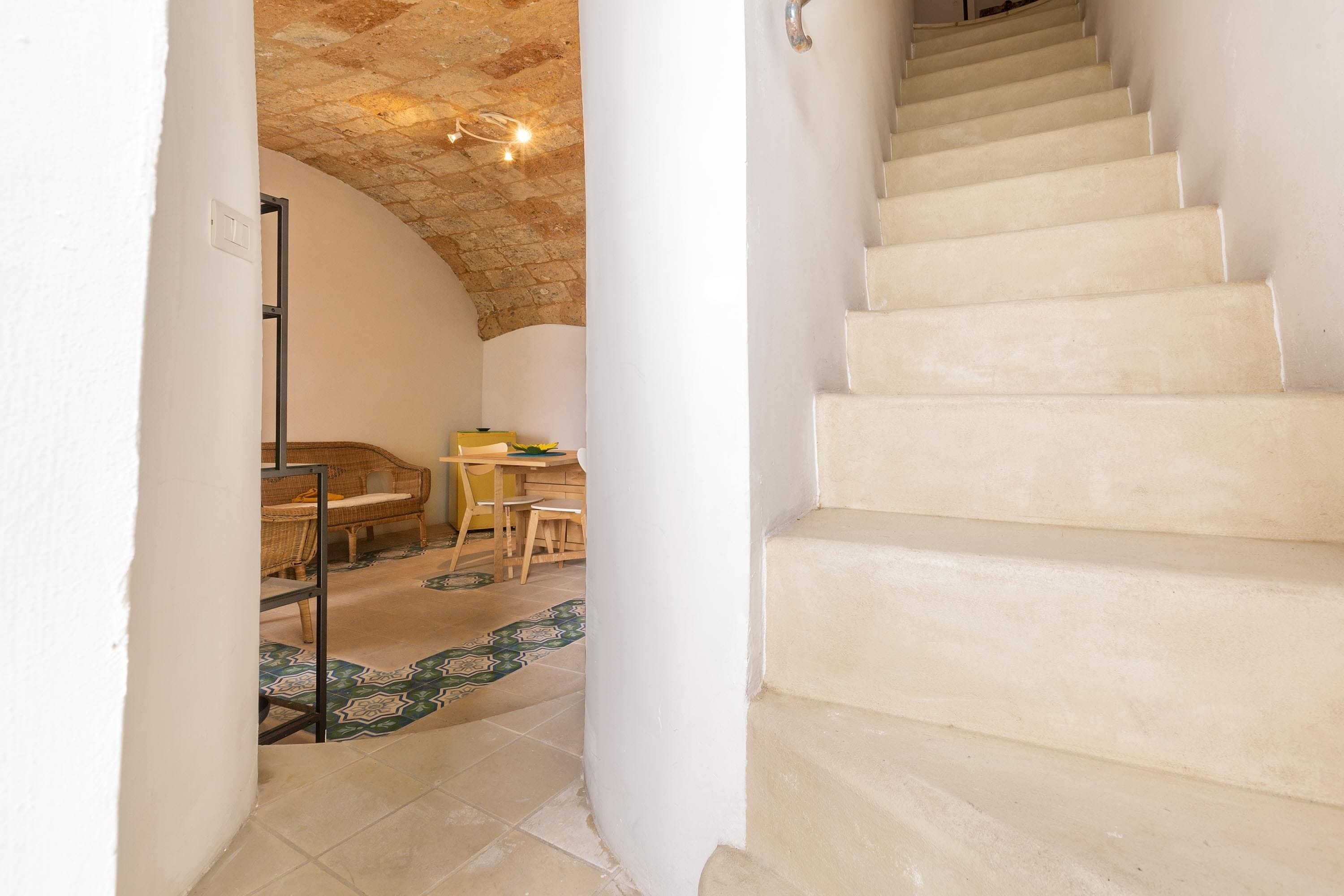 Eine Treppe führt zu einem Raum mit hoher Decke und einem gemusterten Boden.