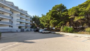A multi-story residential building with balconies, a parking area, and surrounding trees. - Appartamento Baiabella (Gallipoli)